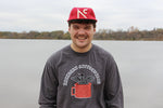 A smiling person wearing the loon long sleeve in front of a lake