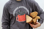 A moderate close up of the loon long sleeve with the text Northern Coffeeworks and a man's arm holding a bundle of wood